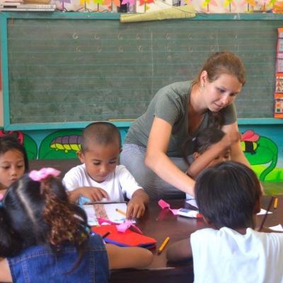 A Childcare volunteer helps a group of young children with a colouring excercises in the Philippines. A Projects Abroad volunteer working with children in the Philippines teaches colouring exercises.